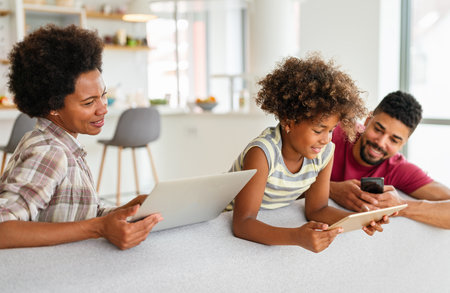 Happy african american family using digital tablet, computer, smartphonesの写真素材