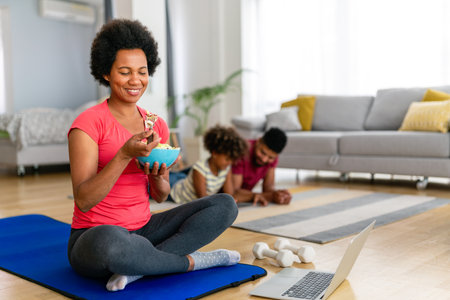 African american woman with family on background eating a healthy salad after workout. Fitnessの写真素材