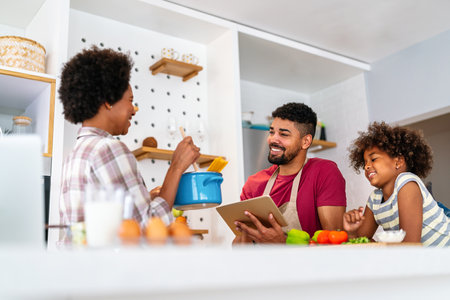 Happy smiling african american parents enjoy weekend play with child in kitchen. Family love conceptの写真素材