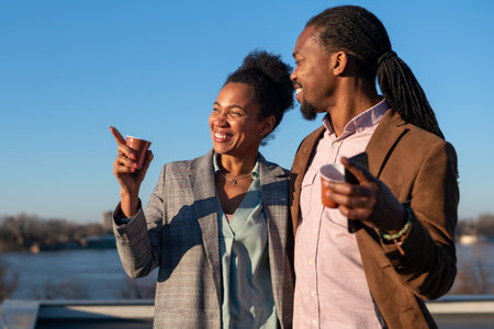 Mid-adult multiethnic business executives enjoy a sunny coffee break on top an office building