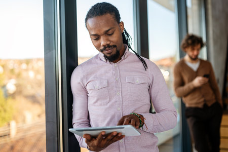Smiling busy young African American business man, manager using tablet computerの写真素材