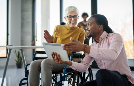 The image includes a person using a wheelchair, depicting inclusivity and teamwork in modern officeの写真素材
