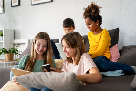 Happy multiethnic teenagers holding technology gadgets using digital devices studying together.の写真素材