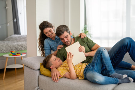 Parents with kid having fun online with application watching video cartoon or playing game on tabletの写真素材