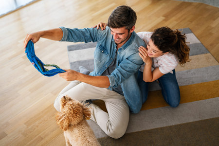 Cute dog enjoys love from owners at home. Couple pets and cares for furry friend, creating a bond.の写真素材