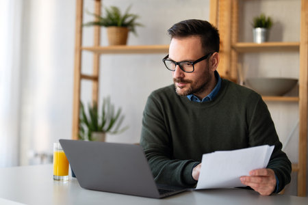 Business man accountant analyst holding documents, work at laptop computer doing online trade marketの写真素材