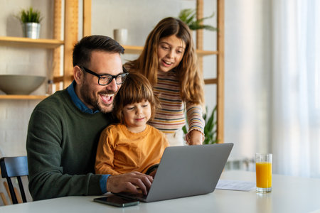 Happy family with kids having fun using laptop together, parent and children relaxing at homeの写真素材