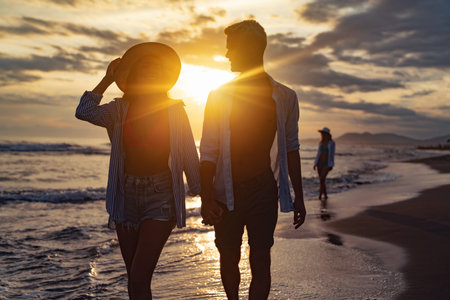 Young beautiful couple walks along the seashore at sunset. Honeymoon. Romantic trip.の写真素材