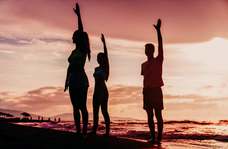 Group of people practicing healthy lifestyle, yoga on beach. Balance in yoga position together.の写真素材