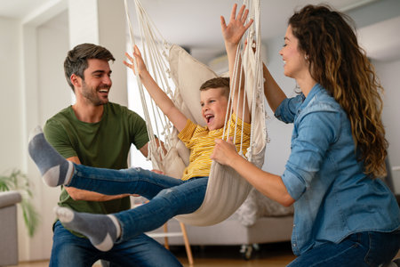 Family from three people cheerfully spends fun time at home together. Parents, kid happiness conceptの写真素材