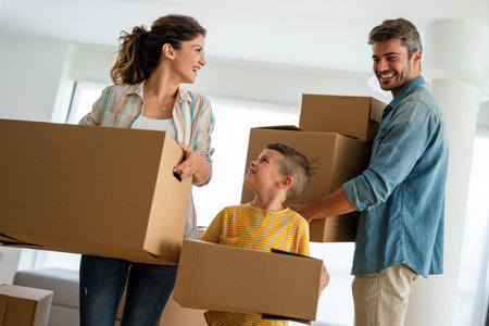 Happy family with cardboard boxes in new house at moving day.の写真素材