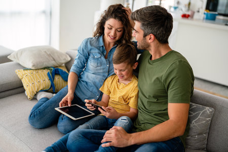 Happy family parents and kid use laptop phone digital tablet at home,の写真素材