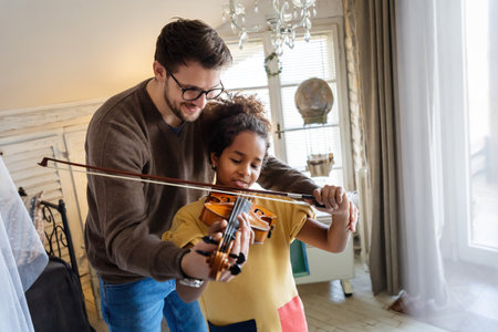 Young man musician teaching a teen girl to play violin. Education music instrument happiness conceptの写真素材