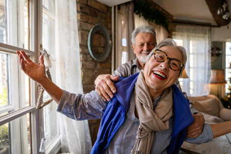 Happy mature woman dancing with her senior husband at home, active healthy senior coupleの写真素材