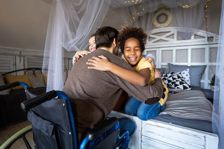 Family gathering, single father in wheelchair sharing love, hugging with diverse children at homeの写真素材