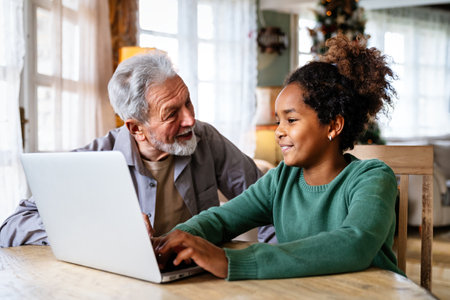 Teenager girl using laptop for education, online gaming, fun, distance learning with grandfatherの写真素材