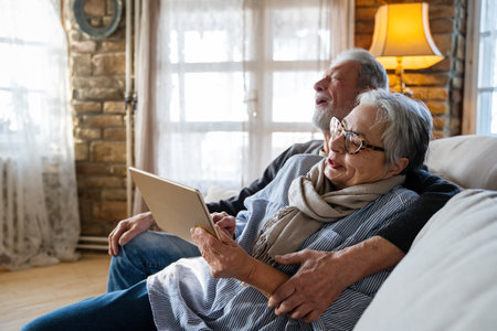 Elderly couple enjoying a tablet. Senior man and woman smiling, bonding over technology.の写真素材