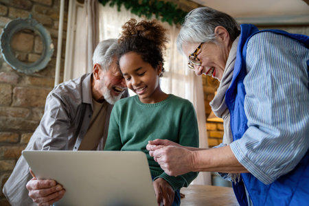 Mature couple with grandchild look at laptop screen and learn how to make video call or use laptop