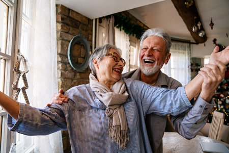 Happy mature woman dancing with her senior husband at home, active healthy senior coupleの写真素材