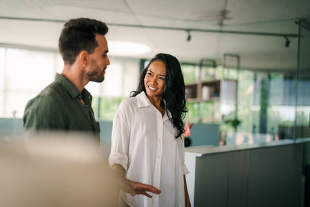 Multiracial colleagues discussing startup project and smiling during workday in office interiorの写真素材