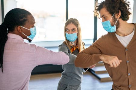 Business people, entrepreneurs with protective face masks elbow bumping while greeting on meetingの写真素材