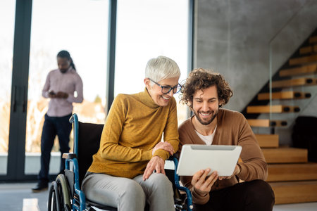 The image includes a person using a wheelchair, depicting inclusivity and teamwork in modern officeの写真素材