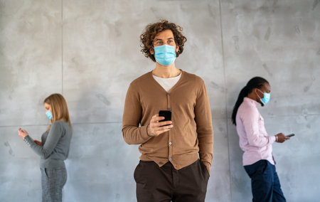 Social isolation at work, university. Young business people face masks in the office trying to workの写真素材