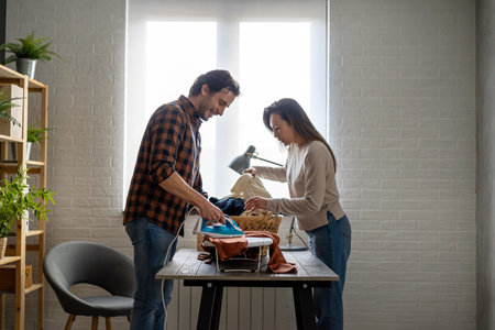 Young couple at home doing household chores and ironing togetherの写真素材