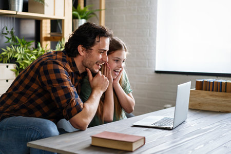 Happy father helping his teenager daughter in homeschooling. People, family technology concept.の写真素材