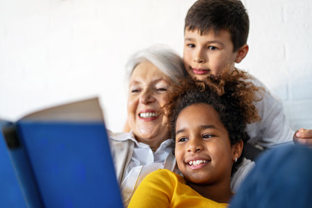 Happy grandmother, nanny helping to mixed race grandchildren with study. Homeschooling conceptの写真素材