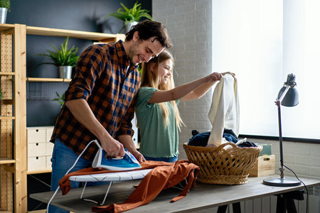 Happy father with daughter at home doing household chores and ironing together.の写真素材