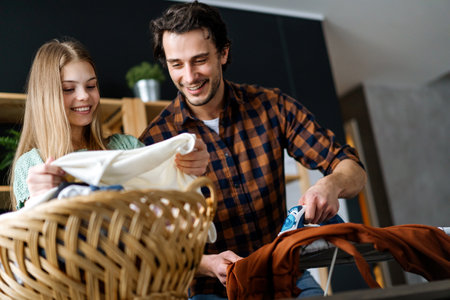 Happy father with daughter at home doing household chores and ironing together.の写真素材