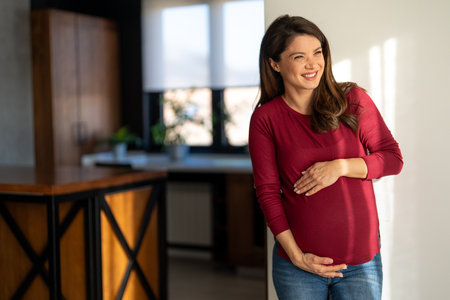 Fit pregnant woman holding hands on her belly, enjoying in the last trimester of pregnancy.の写真素材