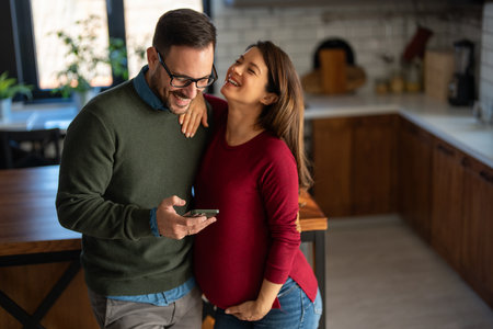 Couple with pregnant woman make video call, taking selfie, spend leisure at home enjoy modern techの写真素材