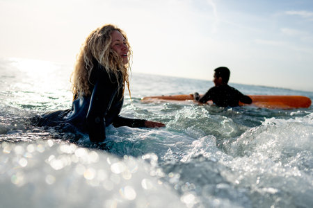 Fit couple surfing at sunset. Surfers friends having fun inside ocean. Sport and vacation conceptの写真素材