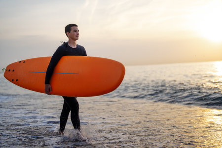 Happy young man is carrying surfboard walking on the beach. Sport, people, summer vacation conceptの写真素材