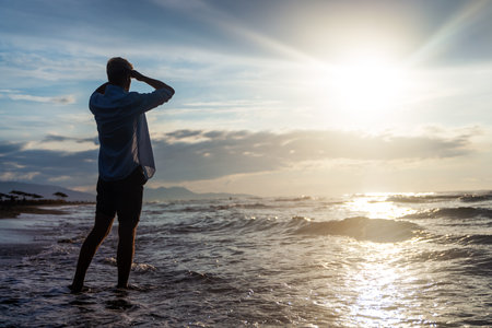 Silhouette of one man on tropical beach during picturesque orange sunset.の写真素材
