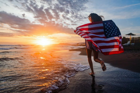 Happy woman running on beach while celebrating independence day and enjoying freedom in USAの写真素材