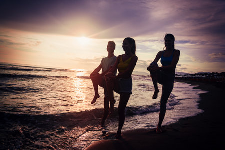 Group of young people, friends in sports clothing jogging while exercising on the beach outdoorsの写真素材