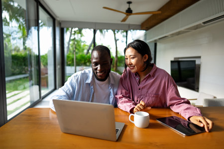 Multicultural couple working remotely, planning finances and investments online. Digital lifestyleの写真素材