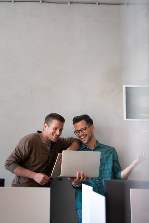Young manager talking with experienced colleague while using computer in office.の写真素材