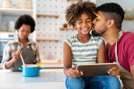 Happy african family having fun with device at home. Black parents and child using digital tabletの写真素材
