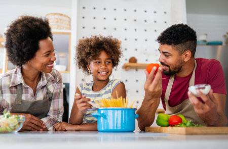 Overjoyed young african american family with kid have fun cooking at home together,の写真素材