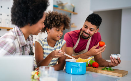 Happy black family in the kitchen having fun and cooking together. Healthy food at home.の写真素材
