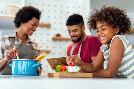 Happy african american parents and child having fun preparing healthy food in kitchenの写真素材