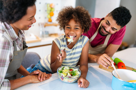 Overjoyed young african american family with kid have fun cooking at home together,の写真素材