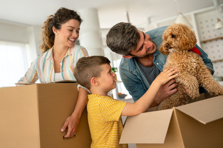 Smiling man and woman enjoy unpacking with child moving to own home. Rent, mortgage conceptの写真素材