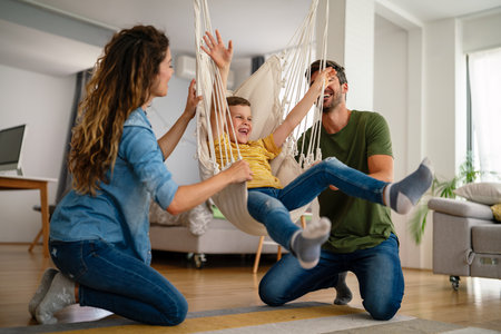 Happy family leisure. Cheerful mother, father and son having fun together on weekend at homeの写真素材
