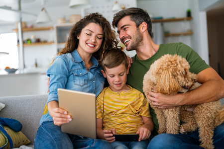 Parents with kid having fun online with application watching video cartoon or playing game on tabletの写真素材