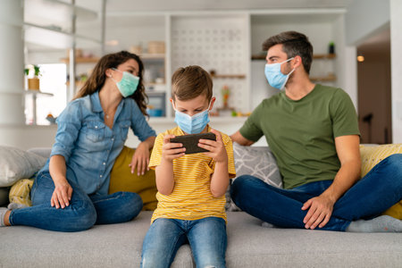 Beautiful young family wearing face masks against coronavirus, pollution, disease and staying homeの写真素材